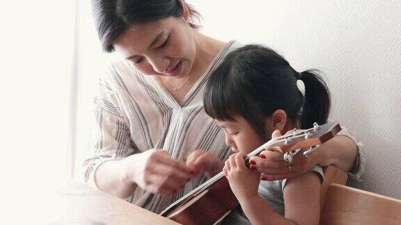 母亲和女儿在家里弹奏尤克里里