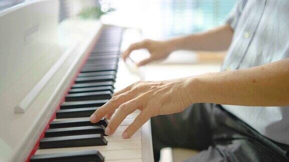 退休后的老人在休息时间在家里的客厅练习弹钢琴的特写
