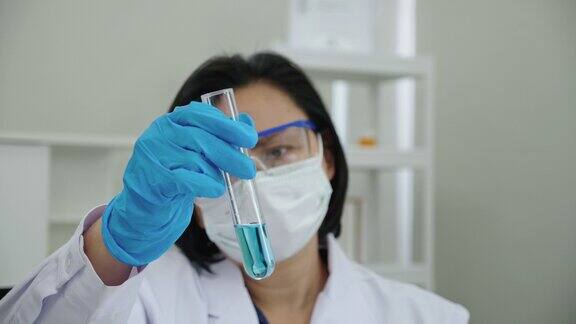 科学家或医生戴医用口罩在医院实验室研究和试验治疗冠状病毒、肿瘤等疾病的药物医疗设备如显微镜、试管医疗技术概念