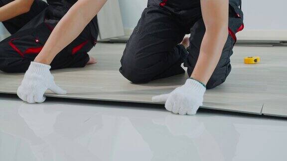 工匠工人在家里地板上安装强化板有吸引力的木匠和木匠检查和计数拼花地板帮助建筑工人修复走廊装修公寓或房子