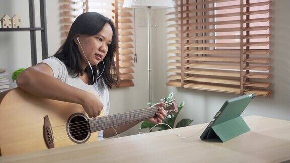 亚洲妇女练习弹原声吉他学习在线教程在家里以技能提升为理念的周末活动