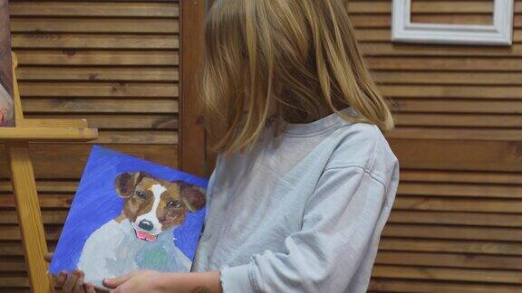 一个小女孩拿着一幅丙烯酸颜料画的杰克罗素梗的肖像