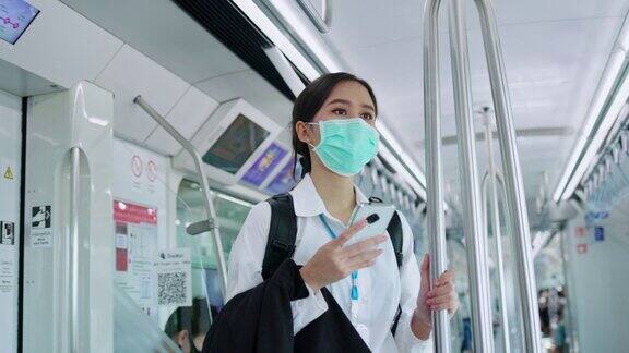 亚洲女商人戴医用口罩预防冠状病毒和PM2.5粉尘乘坐火车或公共交通工具旅行保持社交距离使用智能手机查找信息概念没有锁定