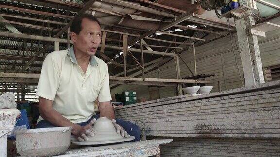 亚洲华人活跃的高级陶工工作在他的工作室与纺陶轮