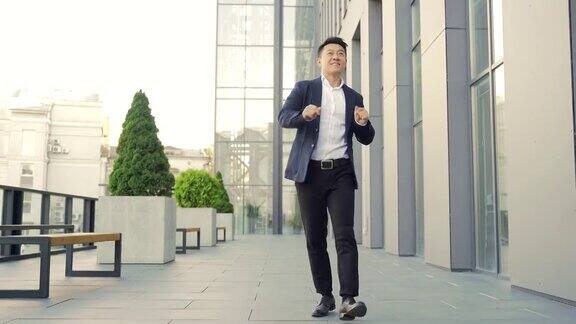 欢快快乐的亚洲商人在走廊上翩翩起舞背景是一座现代化的办公大楼