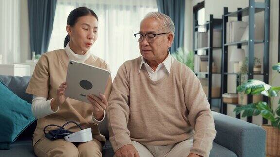 年轻的亚洲女性护理人员个人护理护士教老年男性使用数字平板电脑上的药物指征和指导应用