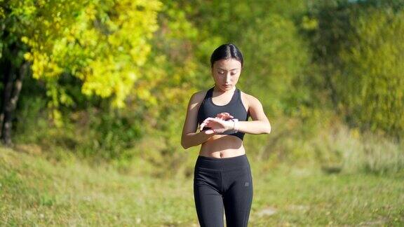 运动亚洲女性看智能手表在现代田径运动员使用使用智能手表健身手环画像