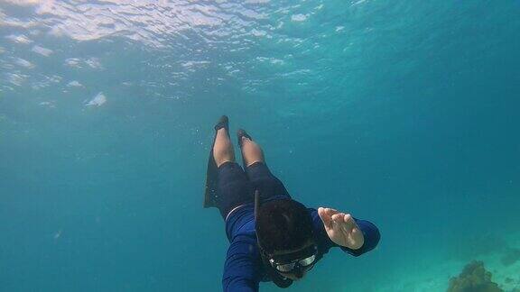 4K青年自由潜水员穿长鳍自拍海豚踢式潜水在清澈的海水珊瑚礁海洋