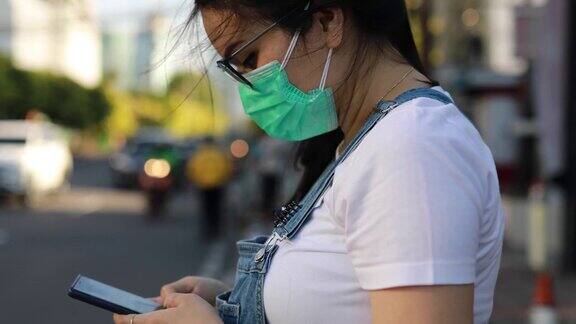 亚洲年轻女子戴着面具在街上等出租车