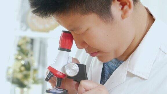 亚洲男生穿着实验服在科学课上使用显微镜教育理念