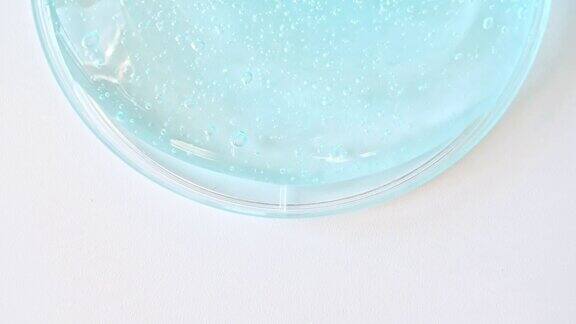 蓝色透明化妆品凝胶霜与分子泡沫流动在平原的白色表面微距镜头