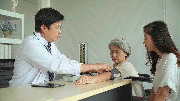 医院里男医生带着血压计给一位老年女病人测量血压