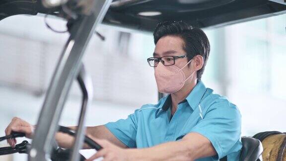 在工业工厂操作叉车的亚洲华人男性仓库工人戴口罩工作