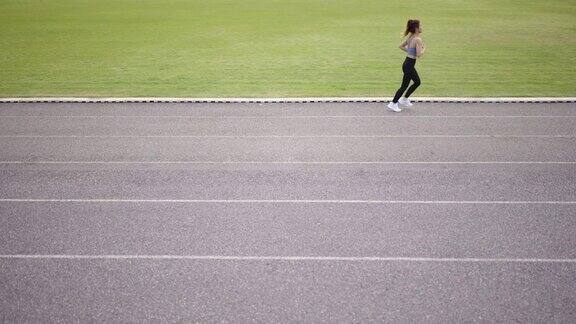 一个女人在跑道上跑步的高视角视频