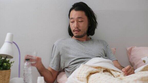 年轻的亚洲男子躺在床上吃药人们保健和医疗