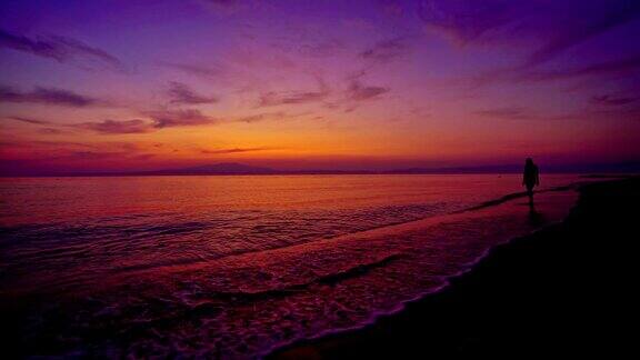 一个女人的剪影享受宁静日落海景从海滩