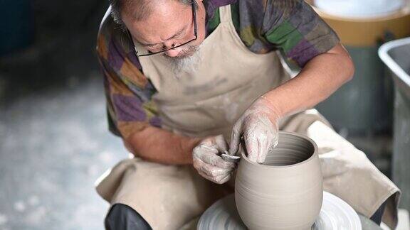 亚洲华人高级泥塑艺术家在他的工作室与纺织陶轮工作
