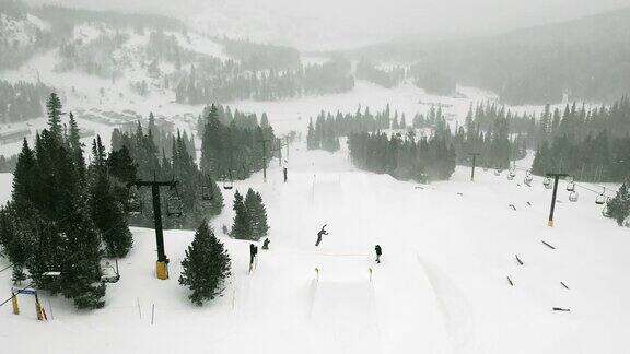 在科罗拉多州博尔德附近的埃尔多拉滑雪度假村在一个下雪的阴天里一个滑雪板在一个森林和滑雪缆车的背景上完成一个“背面540日本”的伎俩