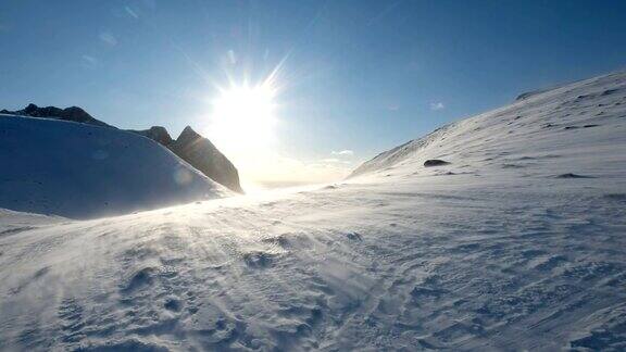 暴风雪吹在有阳光的雪山上