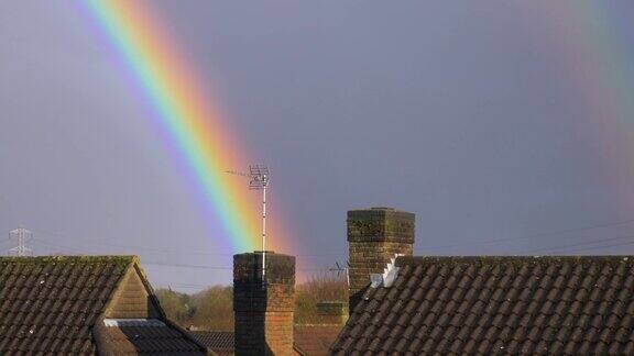 阴天里五颜六色的彩虹越过英国城镇房屋的屋顶和烟囱