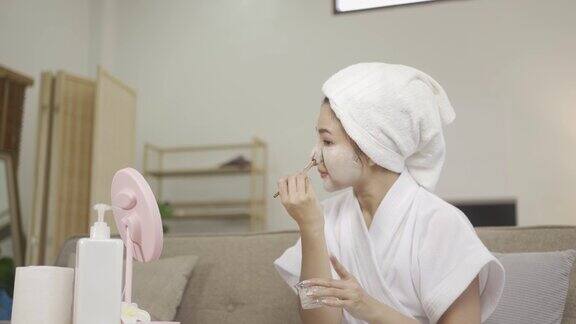 年轻漂亮的亚洲女子在家里化妆头上戴着毛巾在家戴着口罩