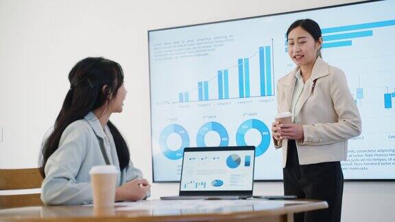 在办公室营销研讨会上专业的女商人培训师与同事进行沟通和解释培训业务和分析在办公室用图表展示
