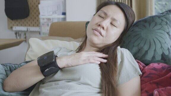 一名妇女正在家里用数字血压计自行测量血压和心率