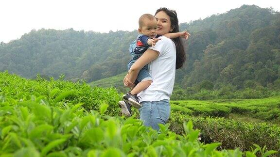 一名亚洲妇女在茶园里抱着她的孩子