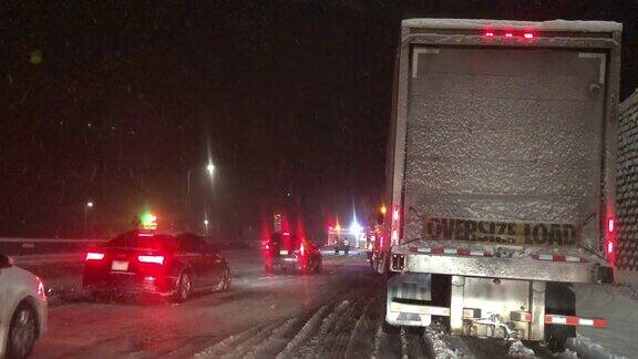 在暴风雪的夜晚在州际公路上被事故和紧急救援人员拦下时从一辆车的前面拍摄的