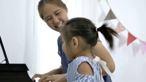 4K:亚洲女孩和妈妈一起弹钢琴的慢镜头