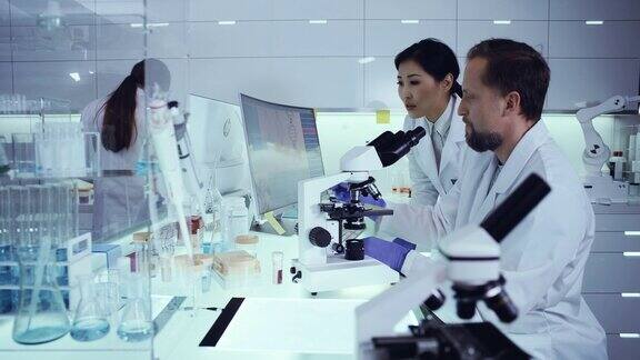 多民族实验室团队处理病原体样本科学家使用显微镜