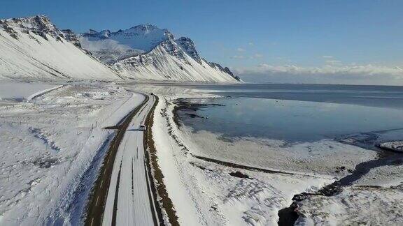 在冰岛东海岸的冬季飞过冰雪覆盖的道路和雪山景观