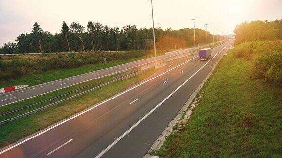 带有货运拖车的商业卡车在空旷的公路上行驶阳光在背景中闪耀