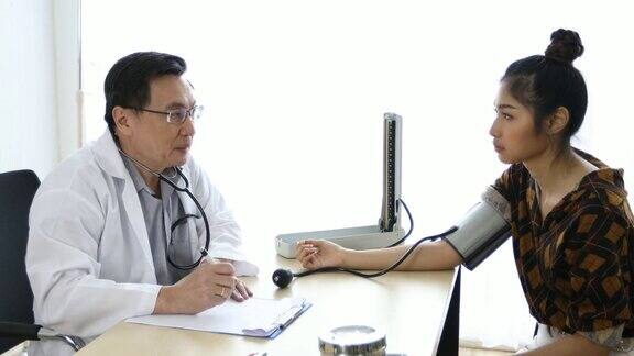 医生在医院的办公室里用血压计给女病人检查