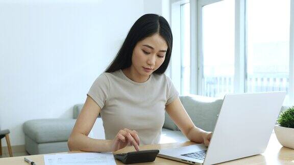 专注的亚洲女性员工在家远程做会计工作