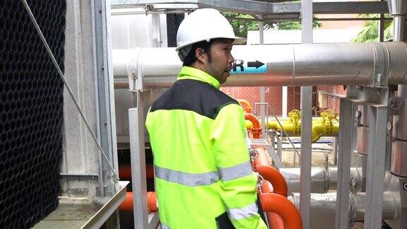 穿着安全制服的亚洲专业电气工程师在工厂现场控制室工作
