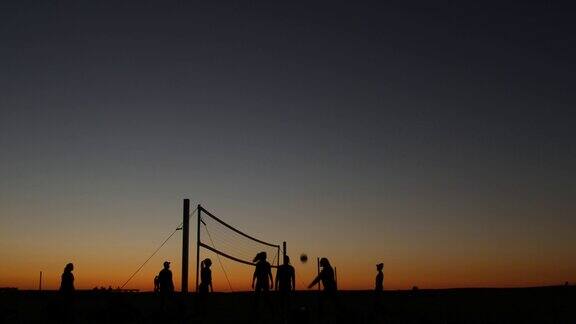 日落时分沙滩球场上排球网的剪影加利福尼亚海岸上的球员