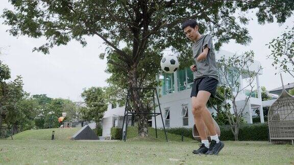 手臂残疾的亚洲男子在球场上练习足球技术