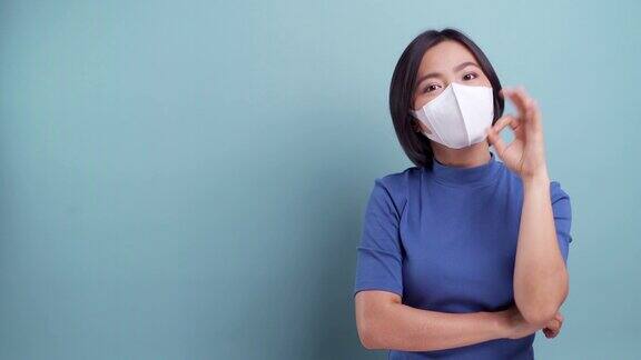 亚洲妇女的肖像戴着卫生口罩隔离在蓝色的背景