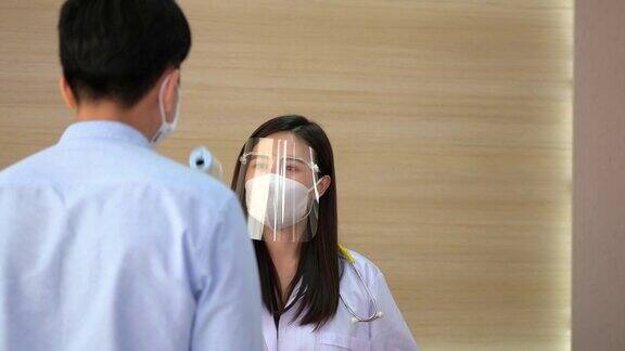 护士戴医用口罩、眼镜用非接触式红外体温计测量患者体温控制医院入口人员体温和健康