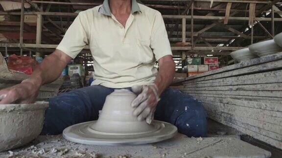 慢镜头亚洲华人活跃的高级陶工在他的工作室用旋转的陶轮工作