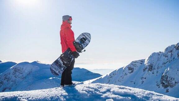 在一个阳光明媚的日子里在山顶上玩滑雪板欣赏冬天的风景