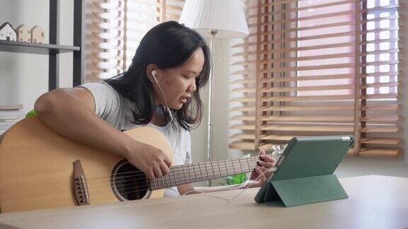 亚洲妇女练习打原声吉他学习在线教程在家里具有技能提升理念的周末活动