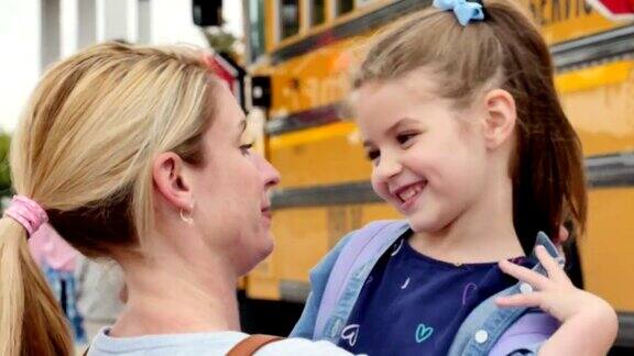 在女儿上幼儿园第一天的校车前充满爱心的妈妈拥抱了她