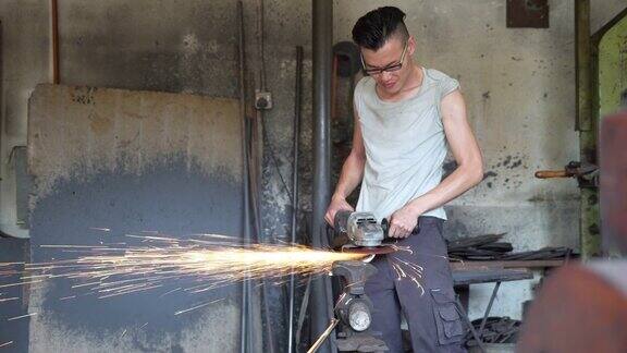 一名亚洲男子在吉隆坡一间铁匠作坊里打磨