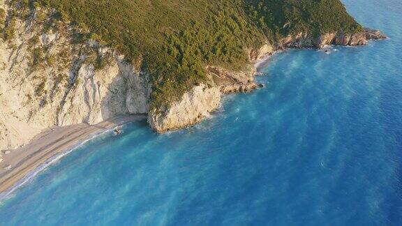 鸟瞰希腊爱奥尼亚岛莱夫卡达美丽的米洛斯海滩日落金色的阳光悬崖般的海岸线和原始的海浪打破了蓝绿色的大海在岸边