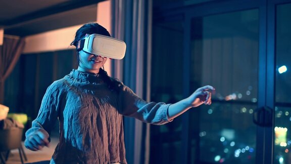 一位亚洲华裔少女戴上VR眼镜在客厅体验3D虚拟游戏体验