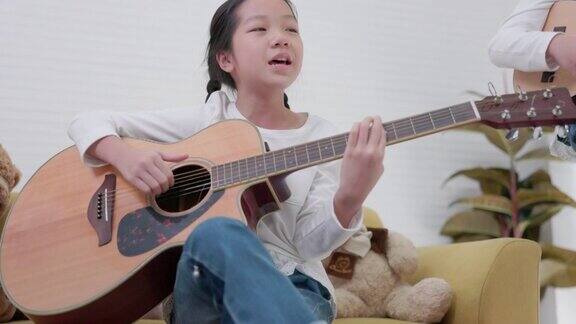 沙发上一个十几岁的女孩在弹原声吉他一个蹒跚学步的小孩在弹吉他
