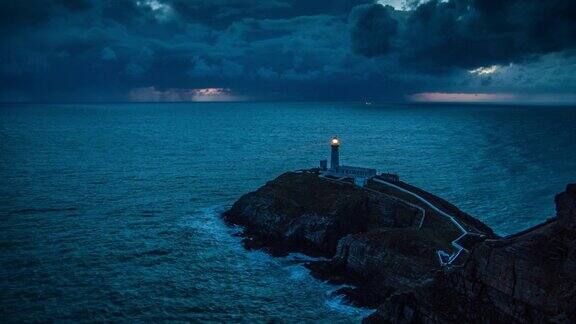 灯塔带着光在暴风雨的海岸线