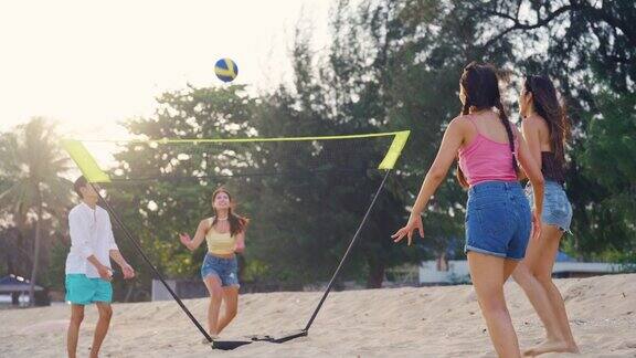一群亚洲青年男女在沙滩上打沙滩排球有吸引力的朋友旅行者玩游戏的乐趣而旅行的假期在热带海岛度假旅行一起